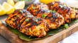© venusvi - Deliciously grilled chicken thighs garnished with fresh herbs and served with lemon wedges.