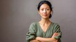 © auraplusminus - Asian woman portrait, arms crossed, green top, confident gaze. Professional, poised, empowered, ideal for business, leadership.
