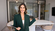 © fizkes - Happy young professional woman pointing hand at modern office interior, looking at camera for portrait, presenting workspace, welcoming onboard, offering job, hiring, business space for rent