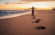 © Soloviova Liudmyla - Freely walking barefoot middle-aged woman on wide sandy beach, leaving deep footstep marks. She is dancing and spinning around with wide-open arms during  sunset golden hour, Tangalle, Sri Lanka.