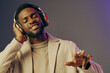 © SHOTPRIME STUDIO - A joyful young African man enjoying music with headphones against a purple background, reflecting relaxation and happiness in a modern lifestyle