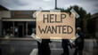 © Lexi - Help wanted sign displayed in window of business with pedestrians outside