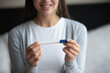 © fizkes - Early detection happiness. Cropped close up happy smiling young woman holding rapid pregnancy test in hands reading result. Expecting mother anticipation future motherhood joy successful ivf concept