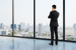 © Who is Danny - Businessman looking out window at modern cityscape in daylight from office, symbolizing future vision, planning, and strategic thinking.