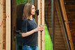 © boomeart - Woman stands near wooden door holding drink outside a cabin in nature