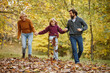 © Stockphotodirectors - Family of three has a joyful weekend in a park surrounded by autumn colors, playing together in fallen leaves while bonding and laughing.
