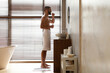 © Prostock-studio - Young Arab man stands in a stylish bathroom brushing his teeth with whitening toothpaste while wrapped in a towel.