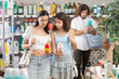 © JackF - Woman with teenage daughter discussing and comparing sunscreen products in personal care store, carefully reading labels to choose best sun protection while father browsing products in background