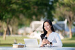 © Phimwilai - Young woman enjoying remote work in a park