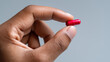 © Curioso.Photography - Fingers holding a red capsule pill symbolizing medicine, treatment, and healthcare.