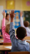 © Curioso.Photography - Young student raising hand during a lesson in a classroom with a teacher in the background.