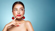 © Oleg Gekman - Portrait of beautiful young woman on blue background, red lipstick and festive makeup, Christmas toy earrings, shiny glowing skin, Winter holidays concept