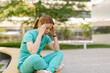 © Westend61 - Healthcare worker sitting outdoors feeling stressed and overwhelmed