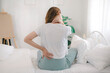 © Aphisara - The young woman experienced body aches while sitting on the bed. She felt pain and stiffness in her shoulders, neck, and back, along with muscle spasms and general discomfort.