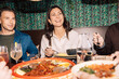 © Maskot - Happy woman having dinner with friends at fine dining restaurant