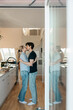 © Maskot - Full length of affectionate young couple kissing each other while standing in kitchen at home