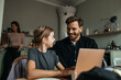© Maskot - Smiling man talking with daughter using laptop at home