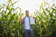© Serhii - Farmer holding corn cob and pesticide bottle in cornfield