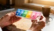 © MI Sumon - Elderly hands holding a colorful pill organizer filled with medication, symbolizing health and daily routine.