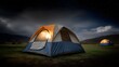 © Thares2020 - Two illuminated camping tents sit in a grassy field under a starry night sky with clouds and distant mountains