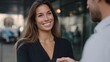 © Thares2020 - A professional woman with a warm smile engages in a handshake with a business associate in an outdoor urban setting