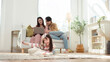 © tonefotografia - Family Stays Together at Home While a Girl Draws on the Floor Near Her Parents Who Relax on the Couch