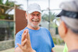 © Daniel - Senior couple playing paddle tennis or padel, outdoors in padel court enjoying and having fun together. Portrait of old man high five with his teammate
