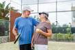 © Daniel - Portrait of couple of mature people playing padel game outdoors in a paddle tennis court together. Old man embracing mature woman teammate