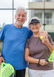 © Daniel - Portrait of couple of mature people playing padel game outdoors in a paddle tennis court together. Old man embracing mature woman teammate looking camera