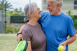© Daniel - Portrait of couple of mature people playing padel game outdoors in a paddle tennis court together. Old man embracing mature woman teammate looking camera