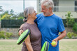 © Daniel - Portrait of couple of mature people playing padel game outdoors in a paddle tennis court together. Old man embracing mature woman teammate looking camera