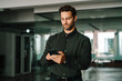 © Stock 4 You - Young Latin businessman holding smartphone telephone device standing in office workplace. European ceo man manager trader using digital technology cellphone phone mobile for business trade work