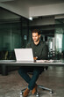 © Stock 4 You - Young professional specialist latin hispanic business man working on laptop pc sit at desk in office. European businessman entrepreneur using computer technology for work online. Full body, vertical