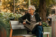 © Maskot - Senior man looking away holding newspaper in hand while sitting on bench