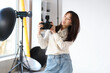 © Pixel-Shot - Female Asian photographer with camera in photo studio