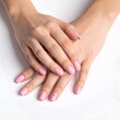 © Mawraa - Two light-skinned hands with pink manicured nails clasped gently on a white background, capturing elegance and simplicity