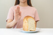 © KMPZZZ - Gluten allergy, asian young woman hand push out, refusing to eat white bread loaf on plate in breakfast food meal at home, girl having a stomach ache. Gluten intolerant and Gluten free diet concept.