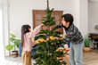 © Kawee - Asian loving father and young daughter decorate Christmas tree in house.