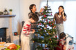 © Kawee - Asian loving couple and young children decorate Christmas tree in house.