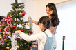 © Kawee - Asian loving mother and young daughter decorate Christmas tree in house.