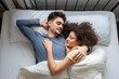 © Kawee - Latino young couple lying down and sleeping on bed in bedroom at home.
