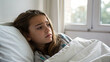 © Hanna - Girl sitting in bed with a serious expression while wrapped in a blanket during the morning at home
