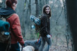 © qunica.com - Two women hike through a forest, carrying gear and dogs along. Friends on a trail share a moment in nature.