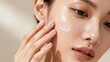 © ibhonk - of young East Asian woman applying a swipe of translucent moisturizer gel on her smooth, healthy cheek skin.