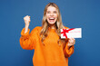 © ViDi Studio - Young happy fun woman she wear yellow sweater casual clothes hold gift certificate coupon voucher card for store do winner gesture isolated on plain blue background studio portrait. Lifestyle concept.