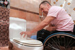 © Alex - A man in a wheelchair placed a roll of toilet paper on the toilet lid.