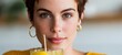 © Z A C - Woman with short hair wearing a yellow top and gold hoop earrings.