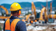 © Maksym - Close-up of construction workerâs profile, yellow hard hat and orange ear defenders, diggers and loaders in blurred motion behind, noisy worksite, protective gear highlighted