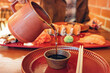 © EdNurg - Hand pouring dark soy sauce into a small bowl, preparing for a sushi meal