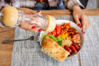 © EdNurg - Woman seasoning a hearty homemade lunch with a pepper or salt mill over a bowl of vegetables, sausages and bread, casual dining moment